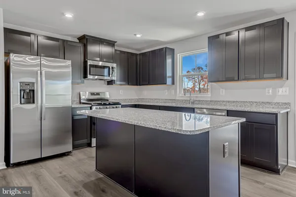 a kitchen with stainless steel appliances granite countertop a refrigerator a sink and a stove