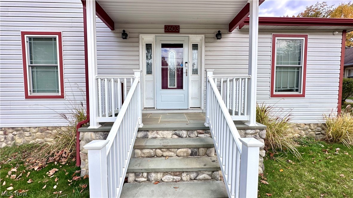 2603 Rockefeller Road Wickliffe, OH 44092 - Photo 2 of 34 Inviting front entrance featuring a stone foundation, natural stone steps, white railing, and a white paneled door with decorative glass inserts