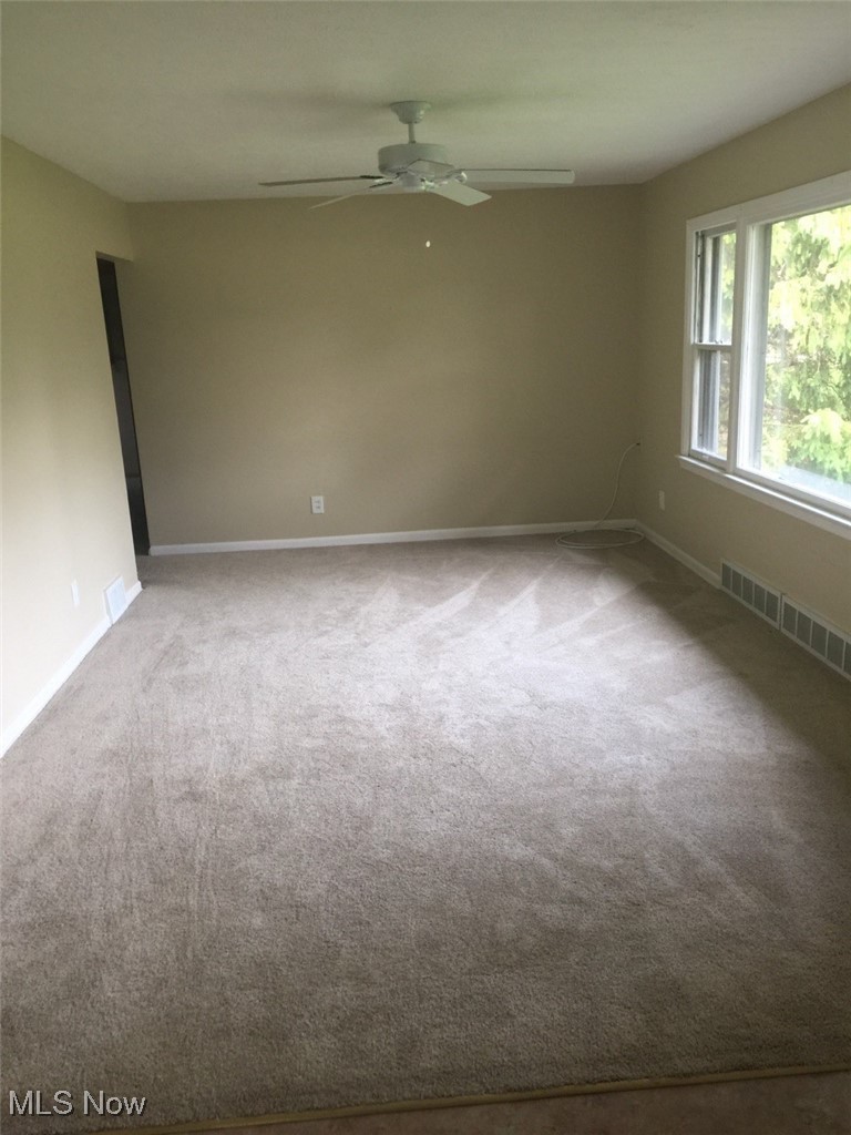 15860 Boston Road Strongsville, OH 44136 - Photo 3 of 7 Spare room with baseboards, visible vents, carpet floors, and ceiling fan