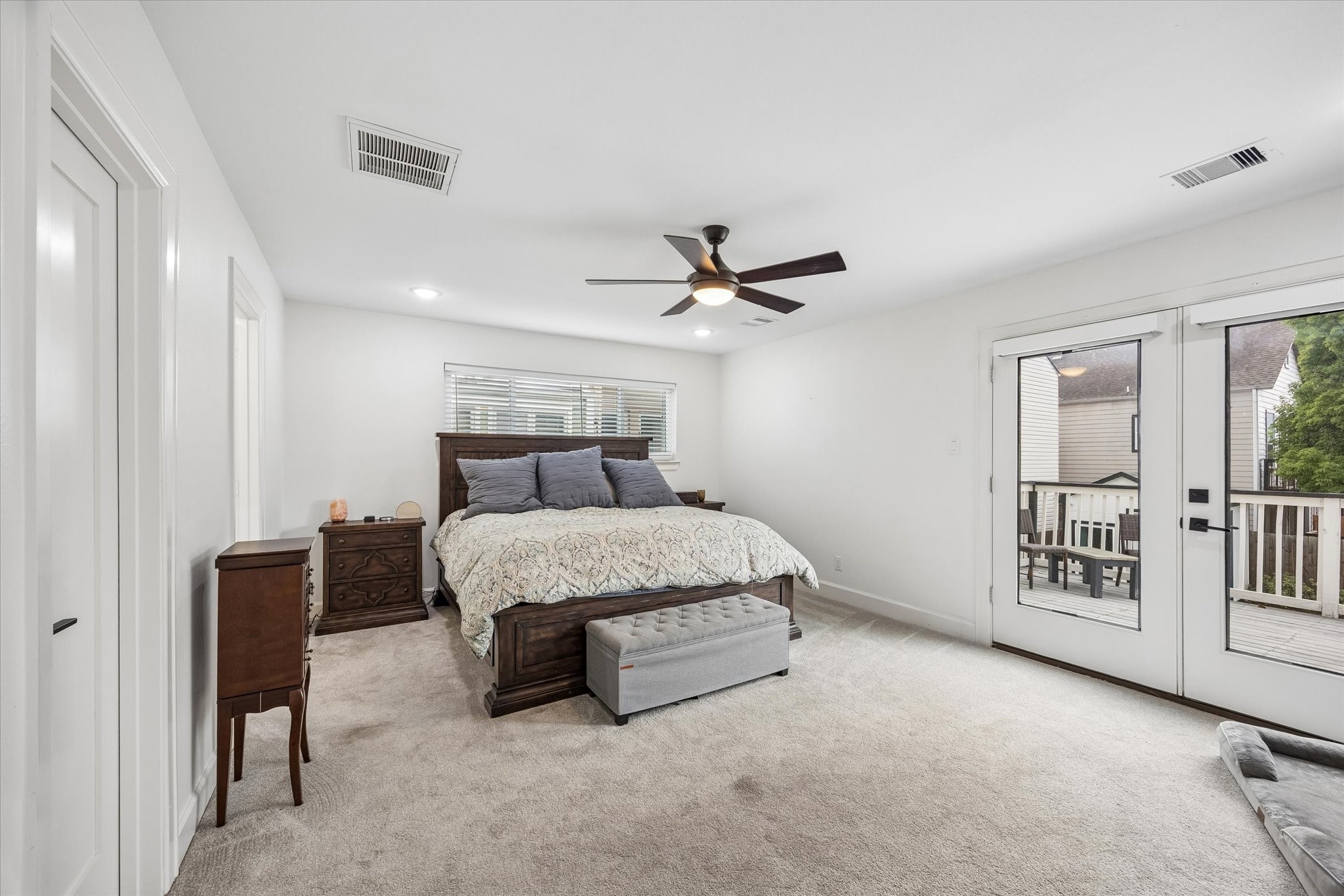 1420 Indiana Street Houston, TX 77006 - Photo 16 of 31 This spacious, bright bedroom features a large bed, ceiling fan, and ample natural light from glass doors leading to a private deck. Neutral tones enhance the serene atmosphere.