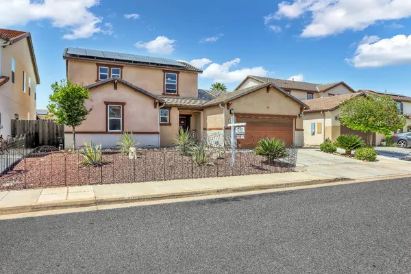 a front view of a house with a yard and potted plants