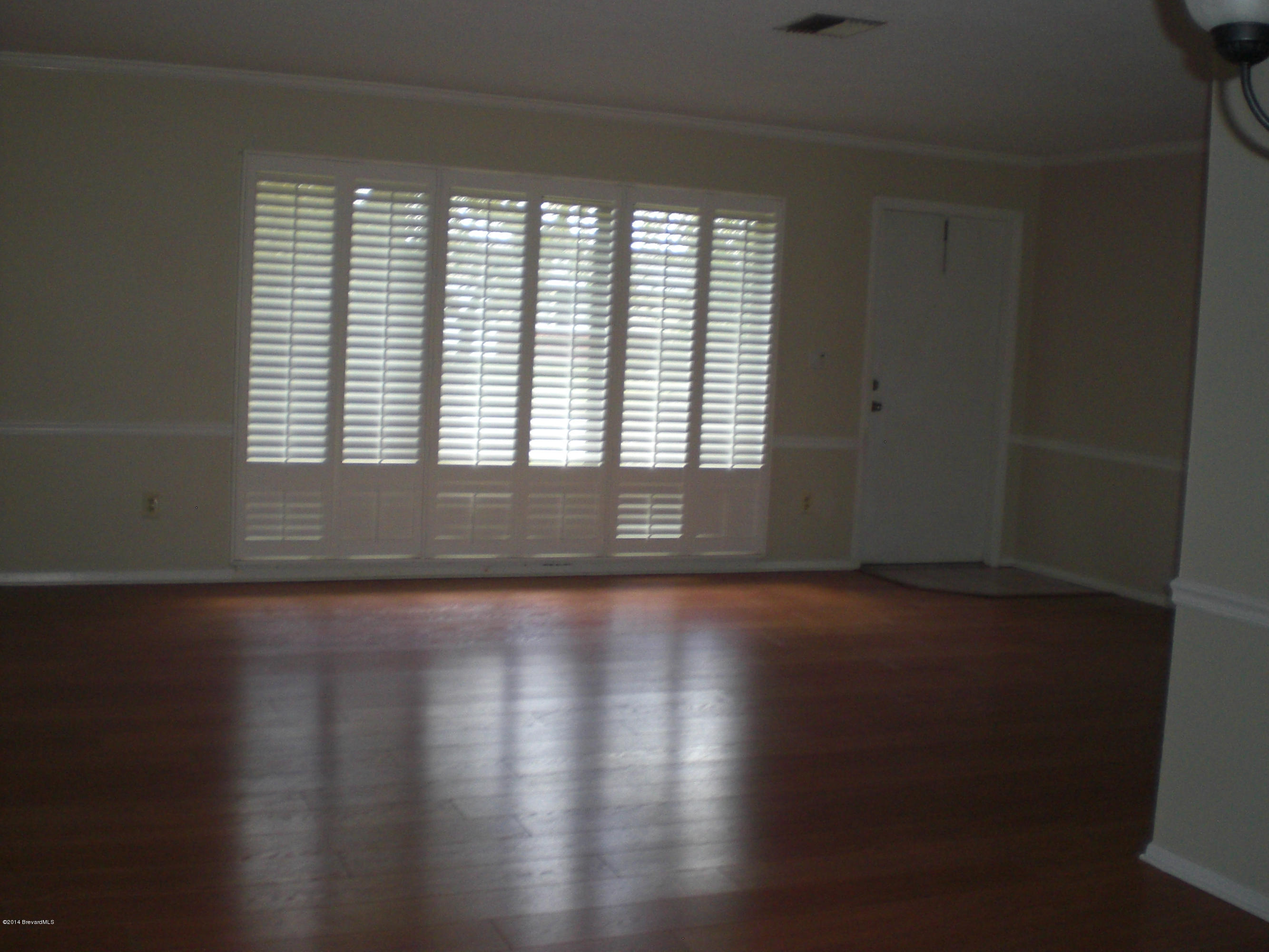 1180 Cotton Road Northeast Palm Bay, FL 32905 - Photo 4 of 18 a view of an empty room with wooden floor and a window