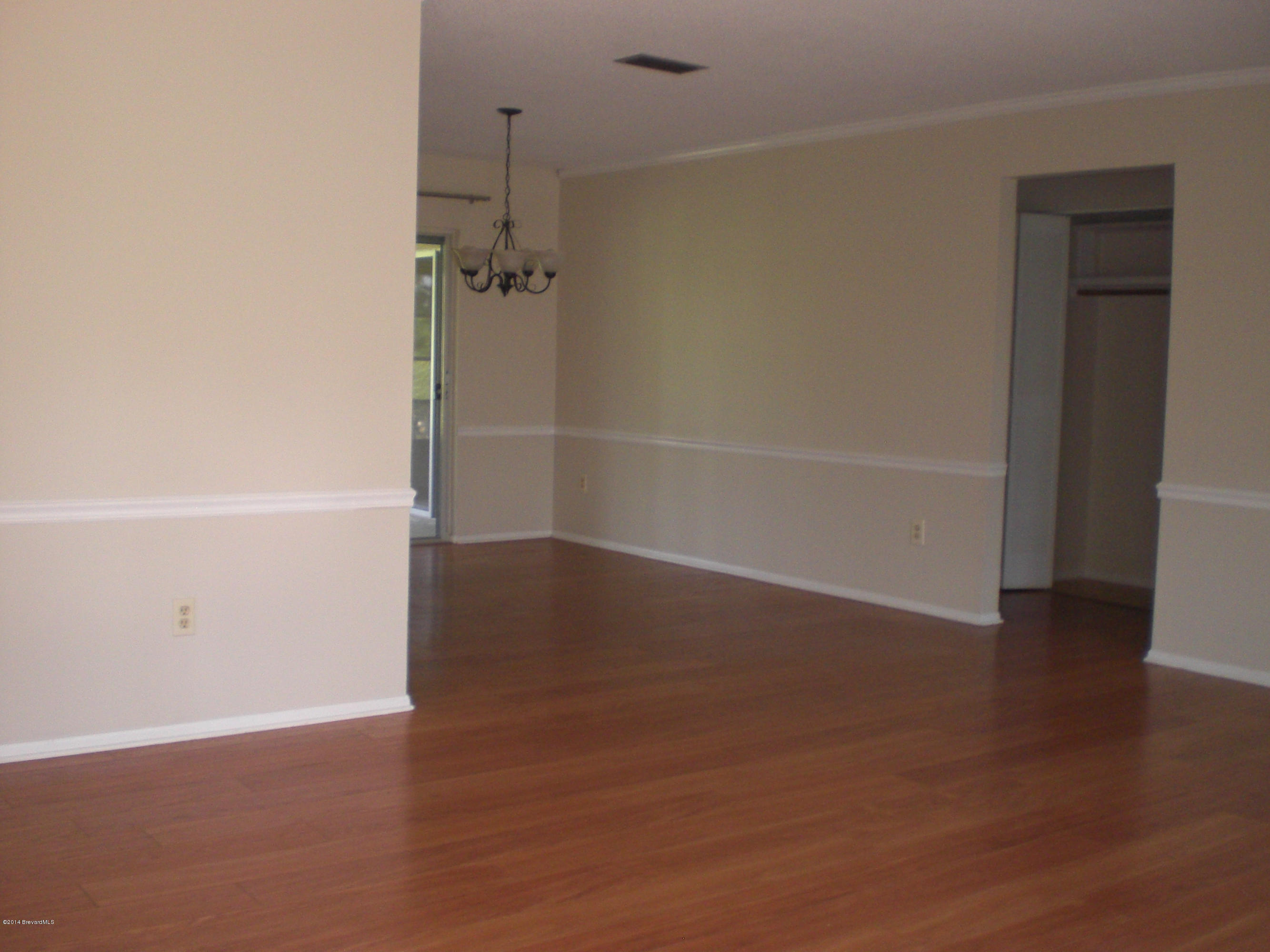 1180 Cotton Road Northeast Palm Bay, FL 32905 - Photo 5 of 18 an empty room with wooden floor and white walls