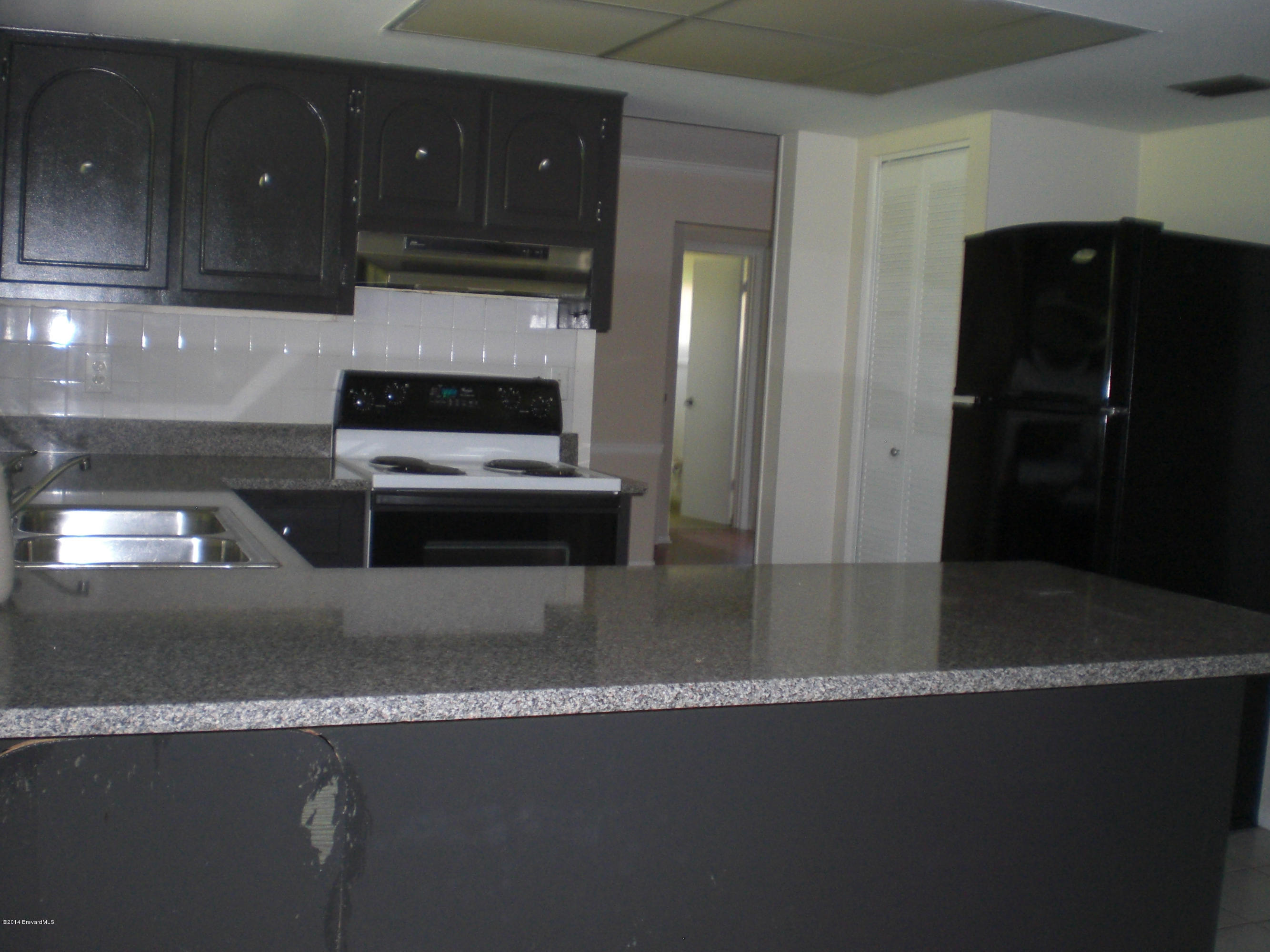 1180 Cotton Road Northeast Palm Bay, FL 32905 - Photo 6 of 18 a kitchen with granite countertop a refrigerator and a stove