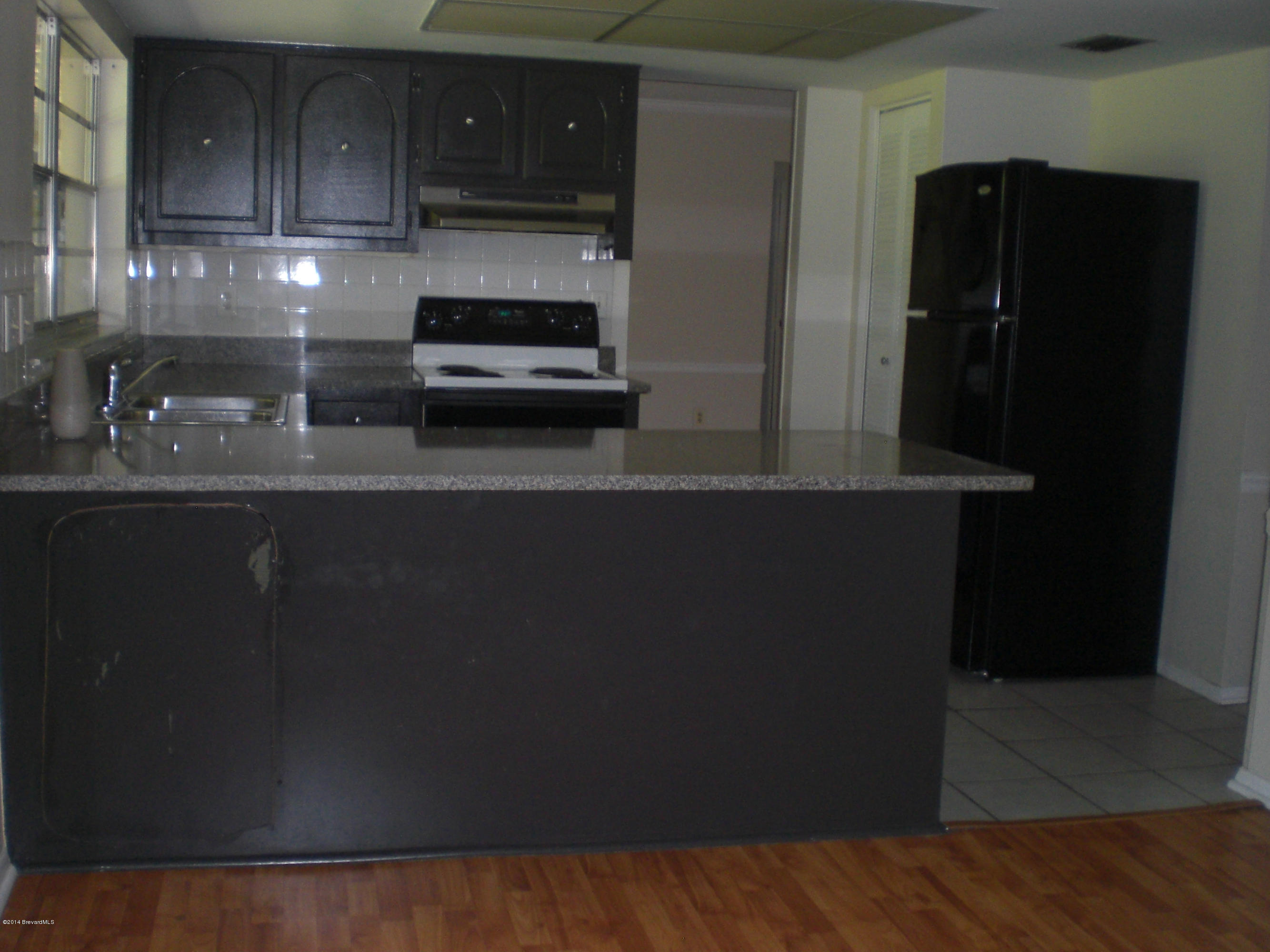 1180 Cotton Road Northeast Palm Bay, FL 32905 - Photo 8 of 18 a kitchen with a refrigerator and cabinets