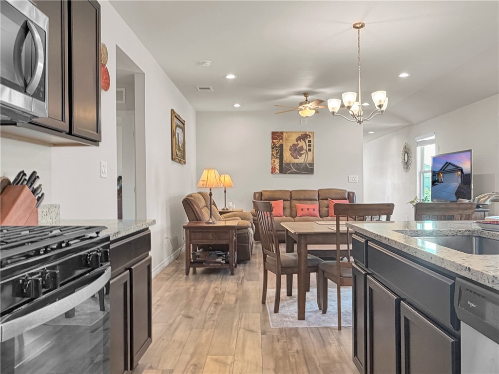 2301 Soothing Street Corpus Christi, TX 78418 - Photo 13 of 25 a open kitchen with stainless steel appliances granite countertop a stove top oven a sink a dining table and chairs with wooden floor