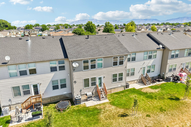 3215 West 450 North West Point, UT 84015 - Photo 31 of 40 Townhome exterior featuring horizontal siding, a gray shingle roof, multiple windows, a rear deck with wooden steps, and a grass yard