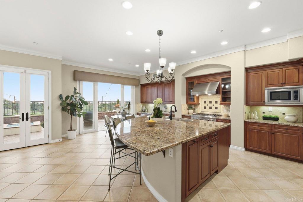 1375 Ravean Court Encinitas, CA 92024 - Photo 18 of 75 a kitchen with stainless steel appliances granite countertop a stove top oven a sink dishwasher a dining table and chairs with wooden floor