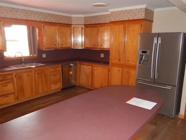 a kitchen with stainless steel appliances granite countertop a refrigerator a sink dishwasher and wooden cabinets