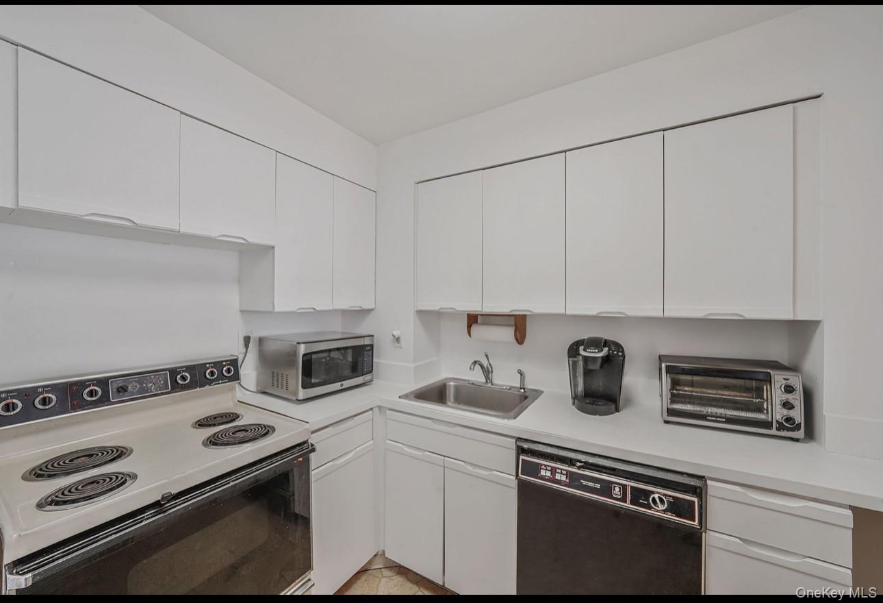 360 Shore Road, Unit 4B Long Beach, NY 11561 - Photo 15 of 28 Kitchen featuring range with electric cooktop, dishwasher, light countertops, white cabinetry, and stainless steel microwave