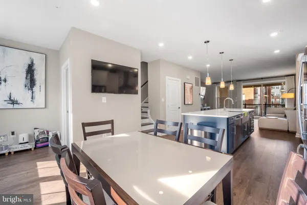 a living room with stainless steel appliances furniture a flat screen tv and a kitchen