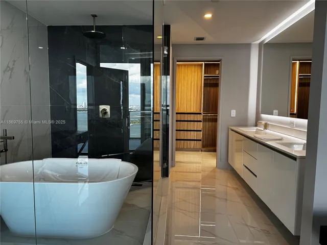 a bathroom with a tub a double vanity sink and a mirror