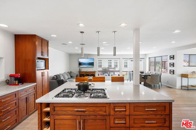 a kitchen with stainless steel appliances granite countertop a stove a sink dishwasher and a dining table with wooden cabinet