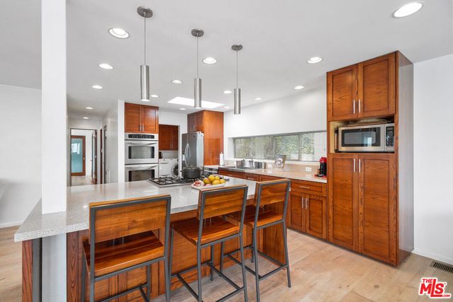 a kitchen with stainless steel appliances granite countertop a stove top oven a sink dishwasher and a refrigerator