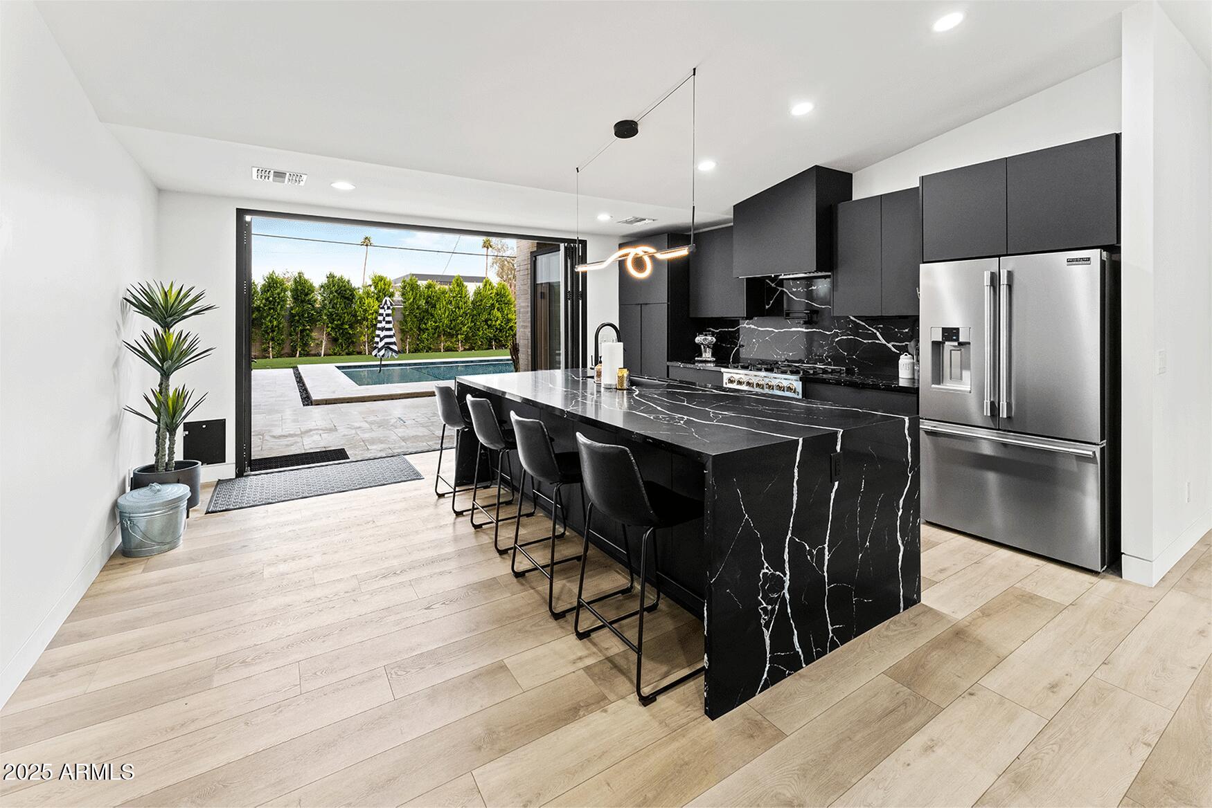 4334 East Lewis Avenue Phoenix, AZ 85008 - Photo 4 of 26 a kitchen with stainless steel appliances granite countertop a stove a refrigerator a sink a dining table and chairs with wooden floor