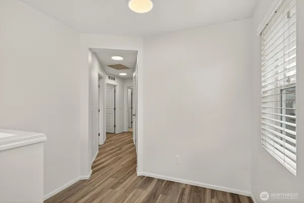 a view of a hallway with wooden floor and a bathroom