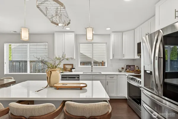 a kitchen with stainless steel appliances granite countertop a sink a stove a kitchen island and chairs