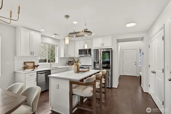 a kitchen with stainless steel appliances granite countertop a table chairs refrigerator and cabinets
