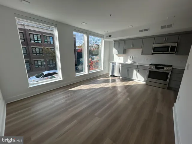 a living room with stainless steel appliances wooden floors and large window