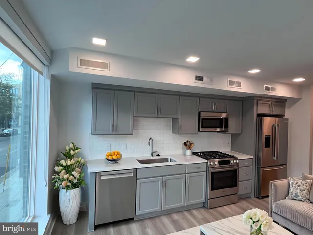 a kitchen with stainless steel appliances a sink a stove a refrigerator cabinets and a window