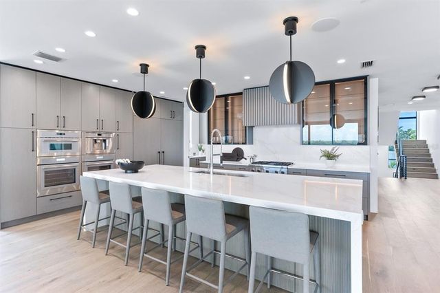 a large kitchen with stainless steel appliances kitchen island granite countertop a sink a stove and a refrigerator