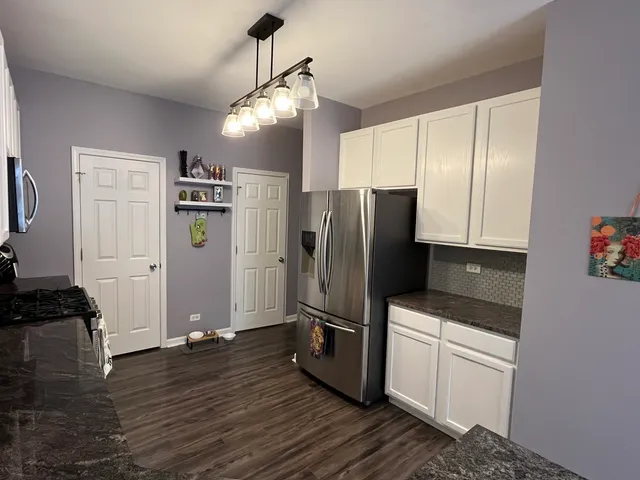 a kitchen with granite countertop a refrigerator and a stove top oven