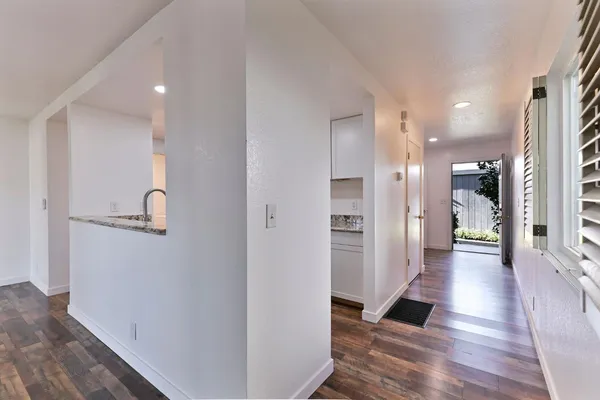 a view of a hallway with wooden floor windows and a living room