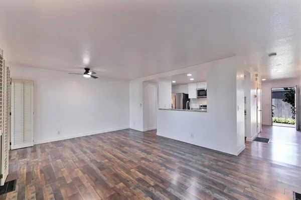 a view of a big room with wooden floor and a kitchen