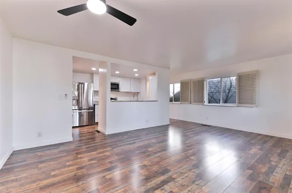 a view of an empty room with wooden floor and a window