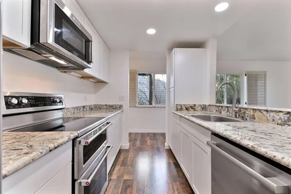 a kitchen with stainless steel appliances granite countertop a stove a sink and a microwave
