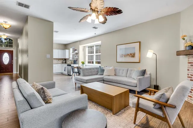 a living room with furniture a chandelier fan and a window