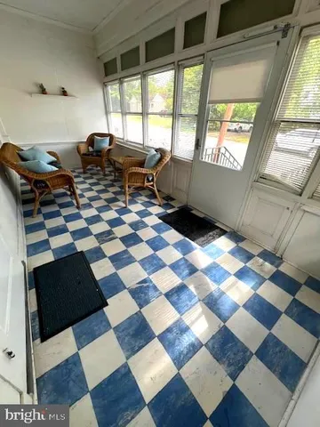 a living room with a black white checkered floor with a gaming machine and dining rug