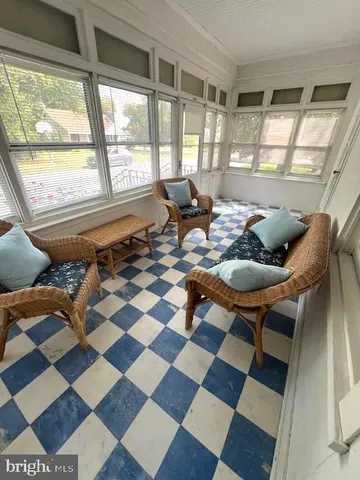 a living room with a black white checkered floor with a gaming machine and dining table