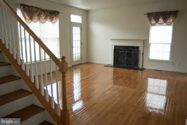 a view of an empty room with wooden floor and a fireplace