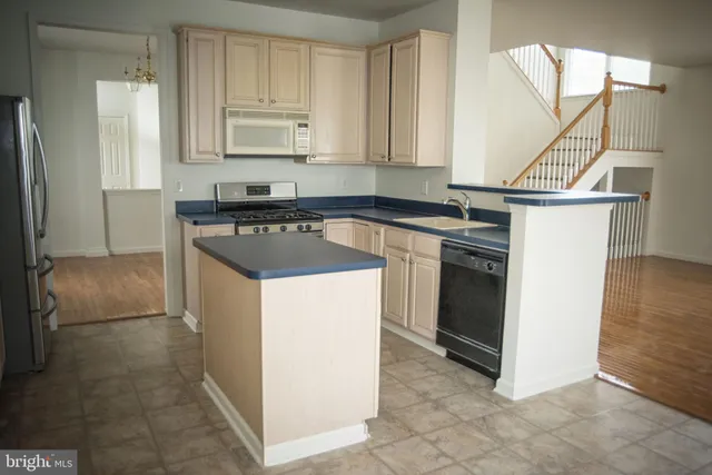 a kitchen with kitchen island granite countertop a sink stove and refrigerator