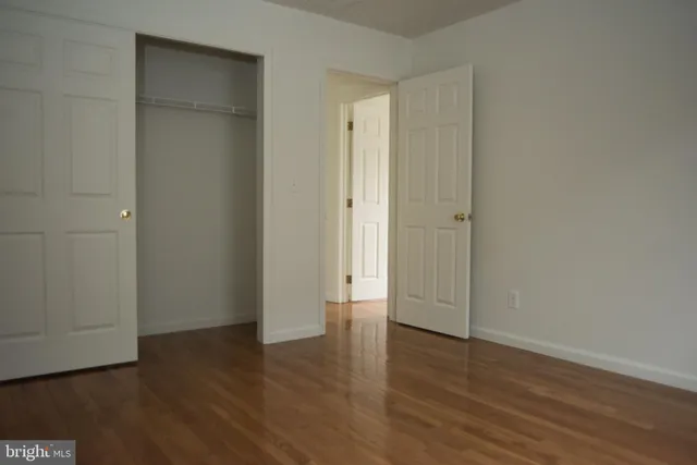a view of an empty room with wooden floor and closet area