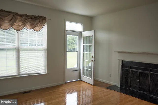 an empty room with wooden floor closet and windows