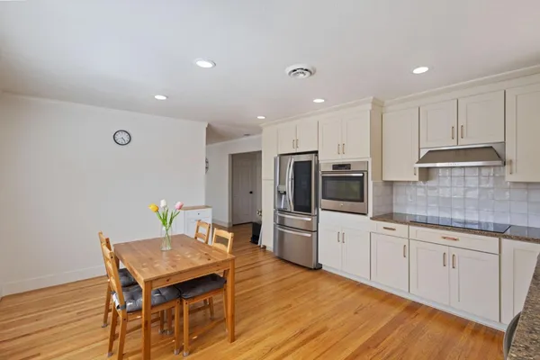 a kitchen with stainless steel appliances kitchen island granite countertop a table chairs sink and cabinets