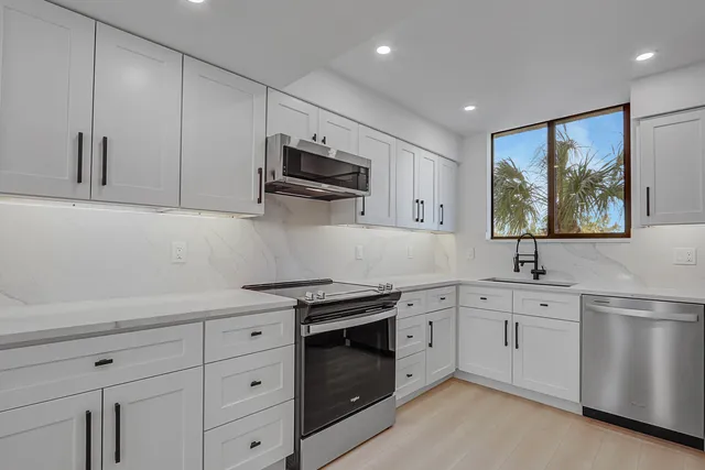 a kitchen with white cabinets stainless steel appliances and sink