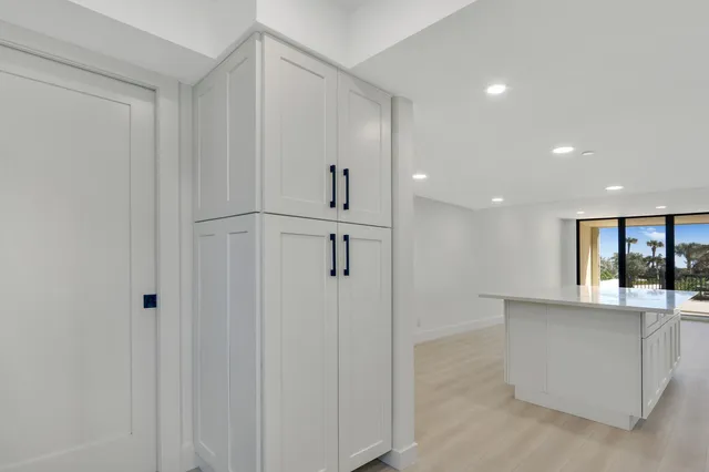 a hallway with kitchen island white cabinets and refrigerator