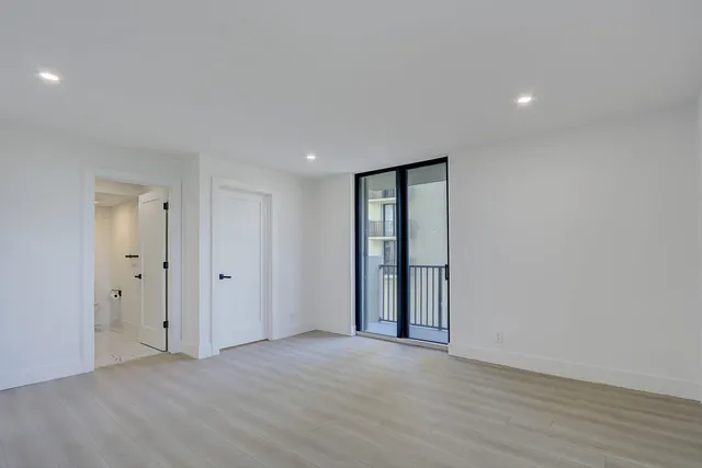 a view of an empty room with wooden floor and closet