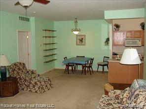 11840 Farmington Road, Unit 59 Livonia, MI 48150 - Photo 5 of 16 Open-concept living area featuring a ceiling fan, wall-mounted shelving, a dining area with chandelier lighting, and a kitchen pass-through with built-in cabinetry and appliances