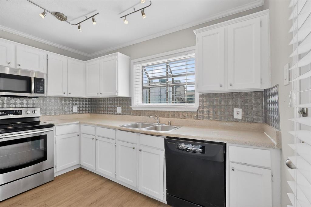 5335 Bent Tree Forest Drive, Unit 237 Dallas, TX 75248 - Photo 16 of 33 a kitchen with stainless steel appliances granite countertop white cabinets a sink a stove a microwave and wooden floors