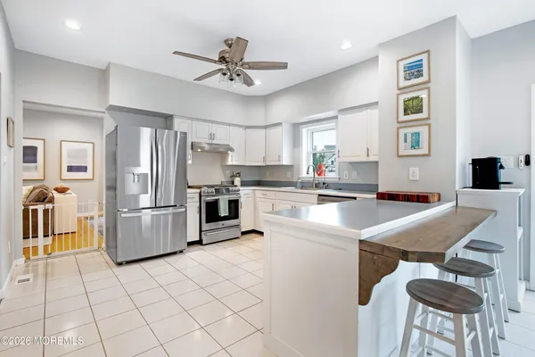 a kitchen with stainless steel appliances a refrigerator a stove a sink dishwasher a dining table and chairs with wooden floor