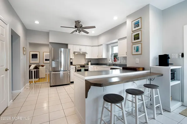 a kitchen with stainless steel appliances granite countertop a sink a stove a refrigerator cabinets and chairs with wooden floor