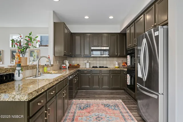 a kitchen with kitchen island granite countertop a refrigerator stove and sink