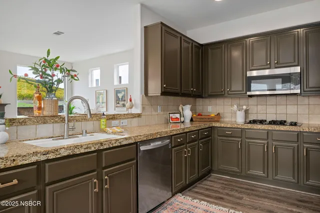 a kitchen with granite countertop a sink cabinets and stainless steel appliances