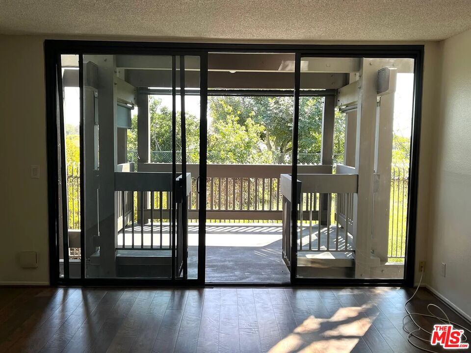 a view of empty room with wooden floor and floor to ceiling window