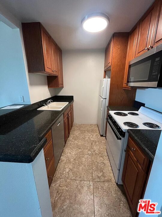 7777 West 91st Street, Unit E2143 Playa del Rey, CA 90293 - Photo 5 of 21 a kitchen with granite countertop a stove top oven sink and cabinets