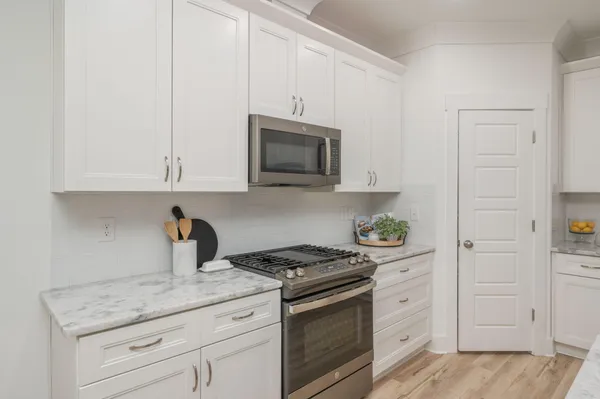 a kitchen with granite countertop white cabinets and stainless steel appliances
